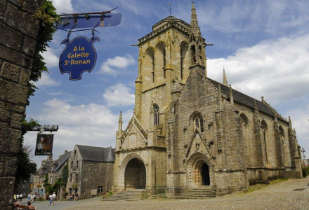 Historische stenen kerk en geplaveide straten nabij Douarnenez, Bretagne, Frankrijk, onder een blauwe lucht.