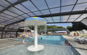 Overdekt zwembad met watertafel en gasten die ontspannen in Flower Camping La Chênaie te Normandië, Frankrijk.