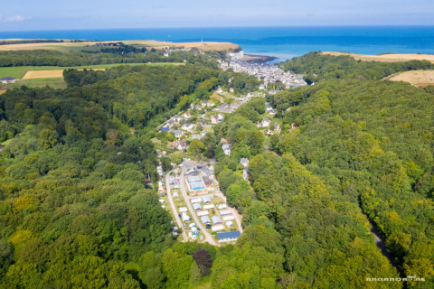 Aerial view of Flower Camping La Chênaie holiday park in Normandy, France, surrounded by lush forest.