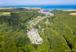 Luftfoto af Flower Camping La Chênaie i Normandiet, Frankrig, omgivet af skov og tæt på havet.