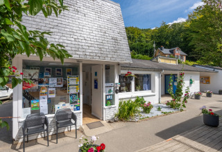 Reception area at Flower Camping La Chênaie in Normandy, France, with plant pots and information displays.