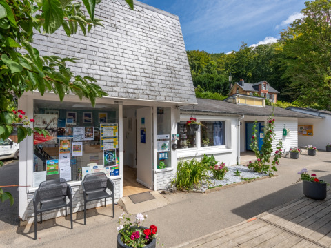 Ingangsgebied van Flower Camping La Chênaie in Normandië, Frankrijk met bloemen, posters en stoelen.