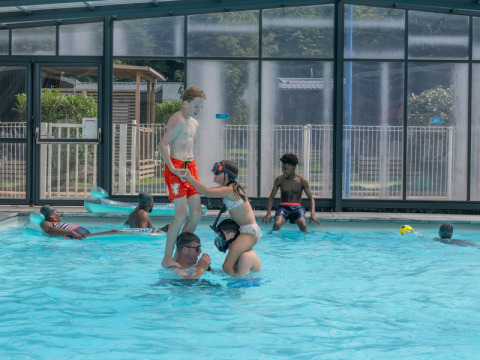 Des enfants jouent dans une piscine couverte au Flower Camping La Chênaie, en Normandie, France.