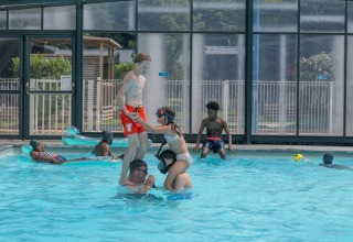 Kinder spielen in einem überdachten Pool im Ferienpark Flower Camping La Chênaie in der Normandie, Frankreich.