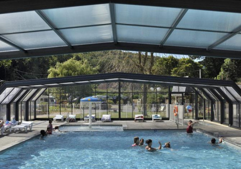 Des familles profitent d'une piscine intérieure sous abri vitré au Flower Camping La Chênaie en Normandie, France