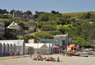Gezinnen op het strand voor hutten en casino aan Flower Camping La Chênaie in Normandië, Frankrijk