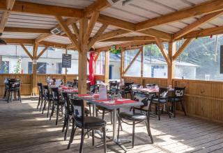 Udendørs spiseområde med træramme og ko-mønstrede stole på Flower Camping La Chênaie i Normandiet, Frankrig.