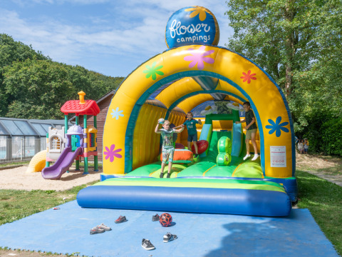 Kinderen genieten op een springkasteel bij Flower Camping La Chênaie, vakantiepark in Normandië, Frankrijk.