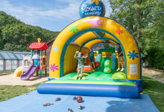 Børn leger på en stor oppustelig hoppeborg ved Flower Camping La Chênaie feriepark i Normandiet, Frankrig.