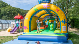 Children having fun on a colorful bouncy castle at Flower Camping La Chênaie holiday park in Normandy, France.