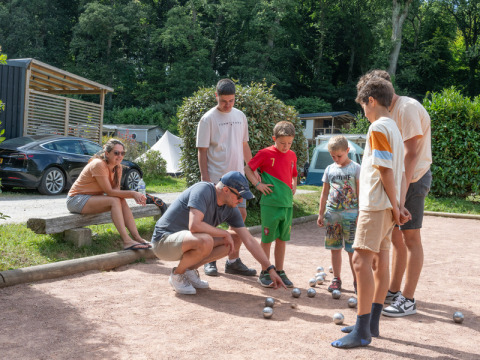 Familie spielt Boule im Freien bei Flower Camping La Chênaie in der Normandie, Frankreich, im Grünen.