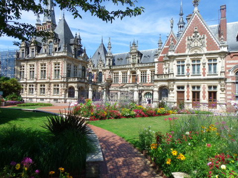 Beautiful historic chateau with ornate towers and gardens at Flower Camping La Chênaie in Normandy, France.