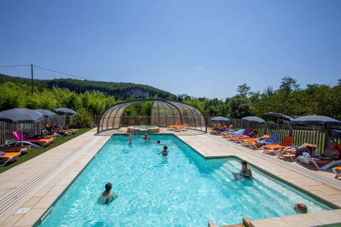 Piscina exterior con tumbonas y sombrillas en Flower Camping La Sagne, parque de vacaciones en Nouvelle-Aquitaine.