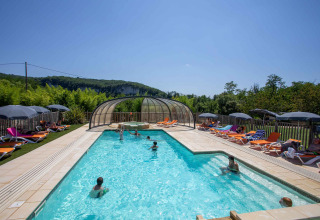 Piscina all'aperto con lettini e ombrelloni al Flower Camping La Sagne, villaggio vacanze in Nouvelle-Aquitaine.