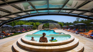 Piscina all'aperto con lettini e famiglia sotto una tettoia a Flower Camping La Sagne, Nouvelle-Aquitaine, Francia.