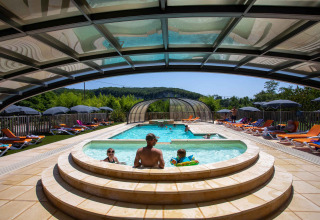 Piscina all'aperto con lettini e famiglia sotto una tettoia a Flower Camping La Sagne, Nouvelle-Aquitaine, Francia.