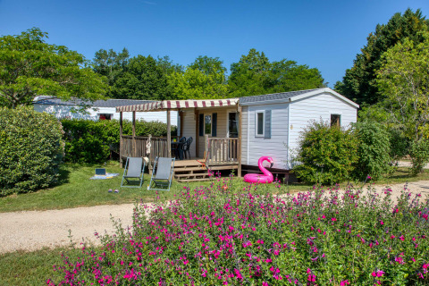 Casa móvil en Flower Camping La Sagne, rodeada de flores y vegetación en Nouvelle-Aquitaine, Francia.