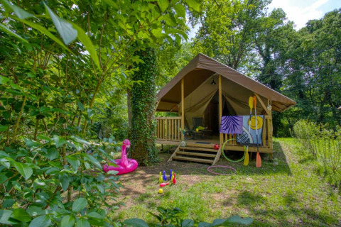Tienda glamping con porche y juguetes al aire libre en Flower Camping La Sagne, Nouvelle-Aquitaine, Francia.