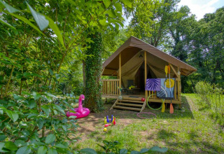 En hyggelig glamping-teltplads i skovområde ved Flower Camping La Sagne, med legeredskaber udenfor.