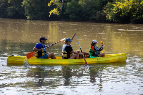 Trois personnes et un chien pagaient dans un canoë jaune à Flower Camping La Sagne, en Nouvelle-Aquitaine.