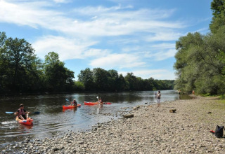 People kayaking and fishing along the riverbank at Flower Camping La Sagne, Nouvelle-Aquitaine, France.