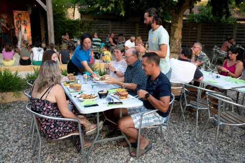 Gäste genießen ein Abendessen im Freien mit Livemusik im Flower Camping La Sagne, Nouvelle-Aquitaine, Frankreich.