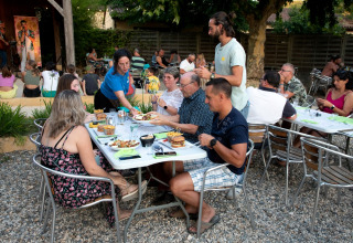 Gasten genieten van een openluchtdiner en livemuziek bij Flower Camping La Sagne in Nouvelle-Aquitaine, Frankrijk.