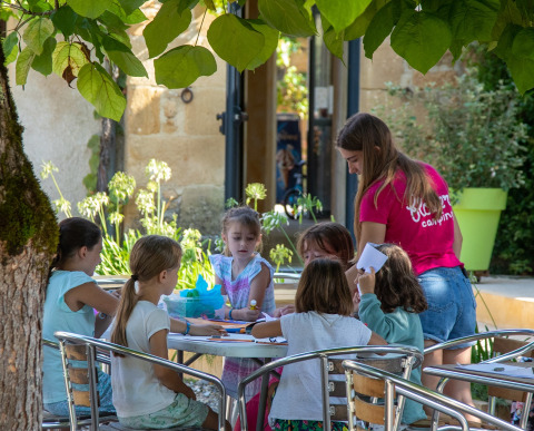 Kinderen zijn creatief bezig aan een buitentafel bij Flower Camping La Sagne in Nouvelle-Aquitaine.