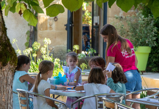 Niños realizan actividades creativas al aire libre en Flower Camping La Sagne, parque vacacional en Nouvelle-Aquitaine.