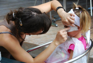 Un adulto crea una maschera facciale su una bambina al Flower Camping La Sagne in Nouvelle-Aquitaine, Francia.