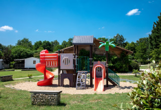 Speeltuin met kleurrijke glijbanen bij Flower Camping La Sagne, vakantiepark in Nouvelle-Aquitaine, Frankrijk.