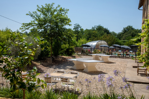 Buitenruimte met tafeltennistafels en zwembad bij Flower Camping La Sagne in Nouvelle-Aquitaine, Frankrijk.