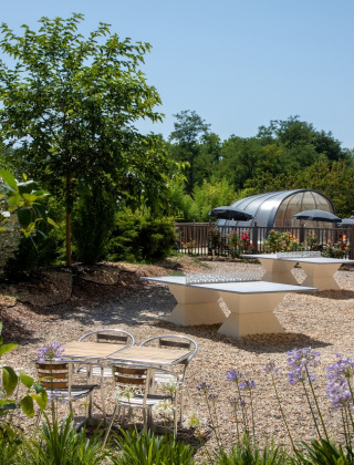 Buitenruimte met tafeltennistafels en zwembad bij Flower Camping La Sagne in Nouvelle-Aquitaine, Frankrijk.