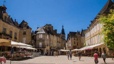 Charming town square with street cafés and historic buildings at Flower Camping La Sagne, Nouvelle-Aquitaine, France.