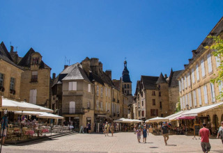 Charming town square with street cafés and historic buildings at Flower Camping La Sagne, Nouvelle-Aquitaine, France.