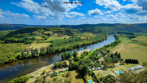Vue aérienne du Flower Camping La Sagne et de la rivière en Nouvelle-Aquitaine, avec paysages verdoyants.
