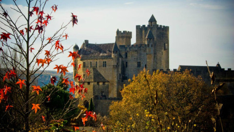 Eine mittelalterliche Burg mit herbstlichen Bäumen in der Nähe von Vitrac, Nouvelle-Aquitaine, Frankreich.
