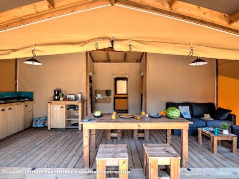 Interior de una tienda safari con muebles de madera, cocina, sofá y mesa de comedor sobre suelo de madera.