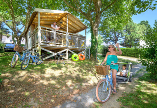 Family enjoying the outdoors at a cabin in Flower Camping Le Conleau holiday park, Brittany, France. Woman cycling.