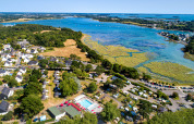 Vista aérea de Flower Camping Le Conleau en Bretaña, Francia, con piscina, casas y paisaje costero.