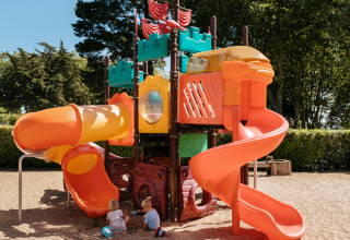 Kinderen spelen in het zand bij een kleurrijke speeltuin op Flower Camping Le Conleau, Bretagne, Frankrijk.