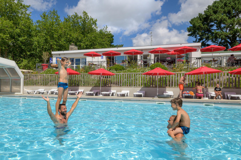 Familias y niños disfrutan en la piscina al aire libre de Flower Camping Le Conleau en Bretaña, Francia.