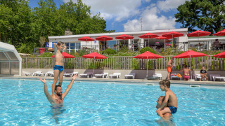 Feriecamping i Bretagne: Børn og voksne leger i swimmingpoolen på Flower Camping Le Conleau.