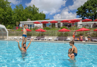 Familias y niños disfrutan en la piscina al aire libre de Flower Camping Le Conleau en Bretaña, Francia.