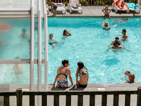 People enjoying a sunny day at the swimming pool at Flower Camping Le Conleau holiday park in Brittany, France.