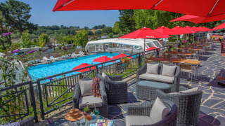 Terrasse med loungeområde, parasoller og udsigt til swimmingpool på Flower Camping Le Conleau i Bretagne.