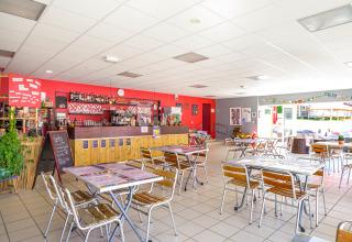 Helles Café im Flower Camping Le Conleau in der Bretagne, Frankreich, mit Tischen, Stühlen und Bar.