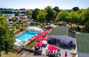 Aerial view of Flower Camping Le Conleau in Brittany, France, with a pool, red umbrellas, and campers.