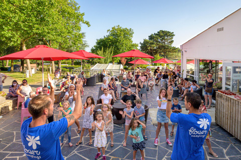 Divertimento in famiglia al Flower Camping Le Conleau in Bretagna, Francia, con attività sotto ombrelloni rossi.