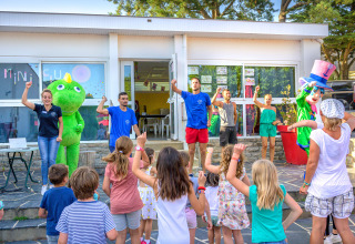 Niños y adultos bailan y juegan con mascotas en Flower Camping Le Conleau, parque vacacional en Bretaña, Francia.